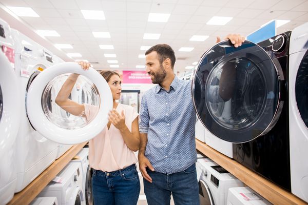 A man and a woman compare front load washers in a store