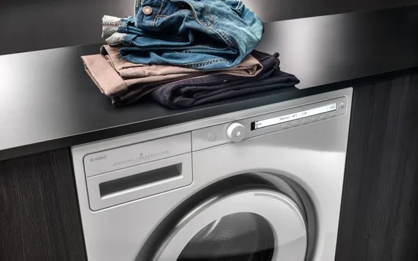 The ASKO W2084W washer featured with a stack of laundry