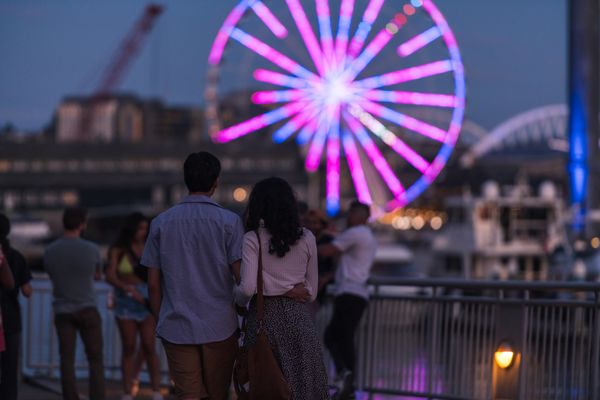 A couple overlooking the Elliott Bay ferris wheel 