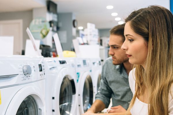 A man and a woman reviewing front load washers in a store 