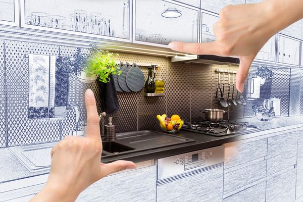 A hand depicting a picture frame around a kitchen blueprint 