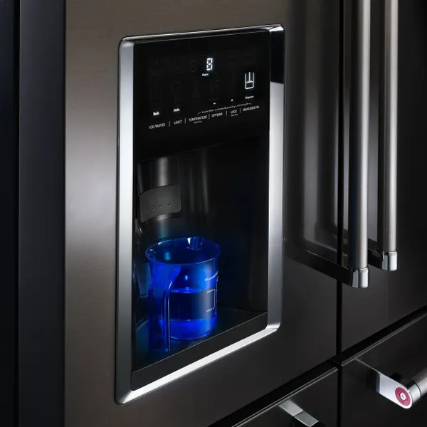 A close-up of the water dispenser on the KitchenAid KRMF706EBS refrigerator 