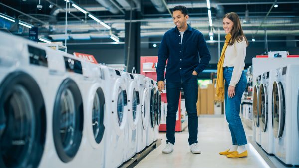 A smiling man and woman inspecting washers in a store 