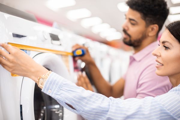 A couple measuring a washer
