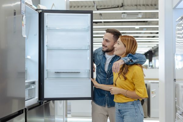 A man and a woman reviewing a refrigerator in a store