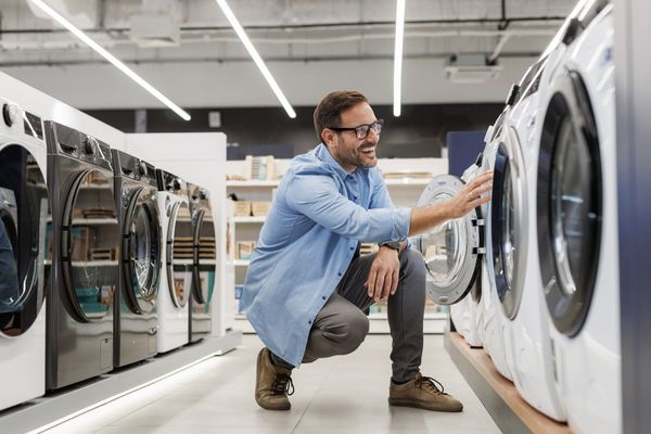 A smiling man reviewing a washer in a store