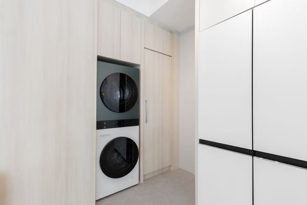A white and green stacked washer dryer unit in wooden cabinetry