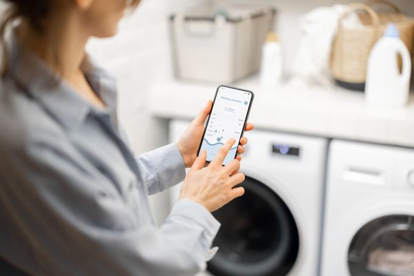 A user selecting a wash setting on a smart device for a smart washer 