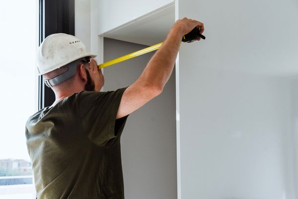 A construction worker measuring a cut out
