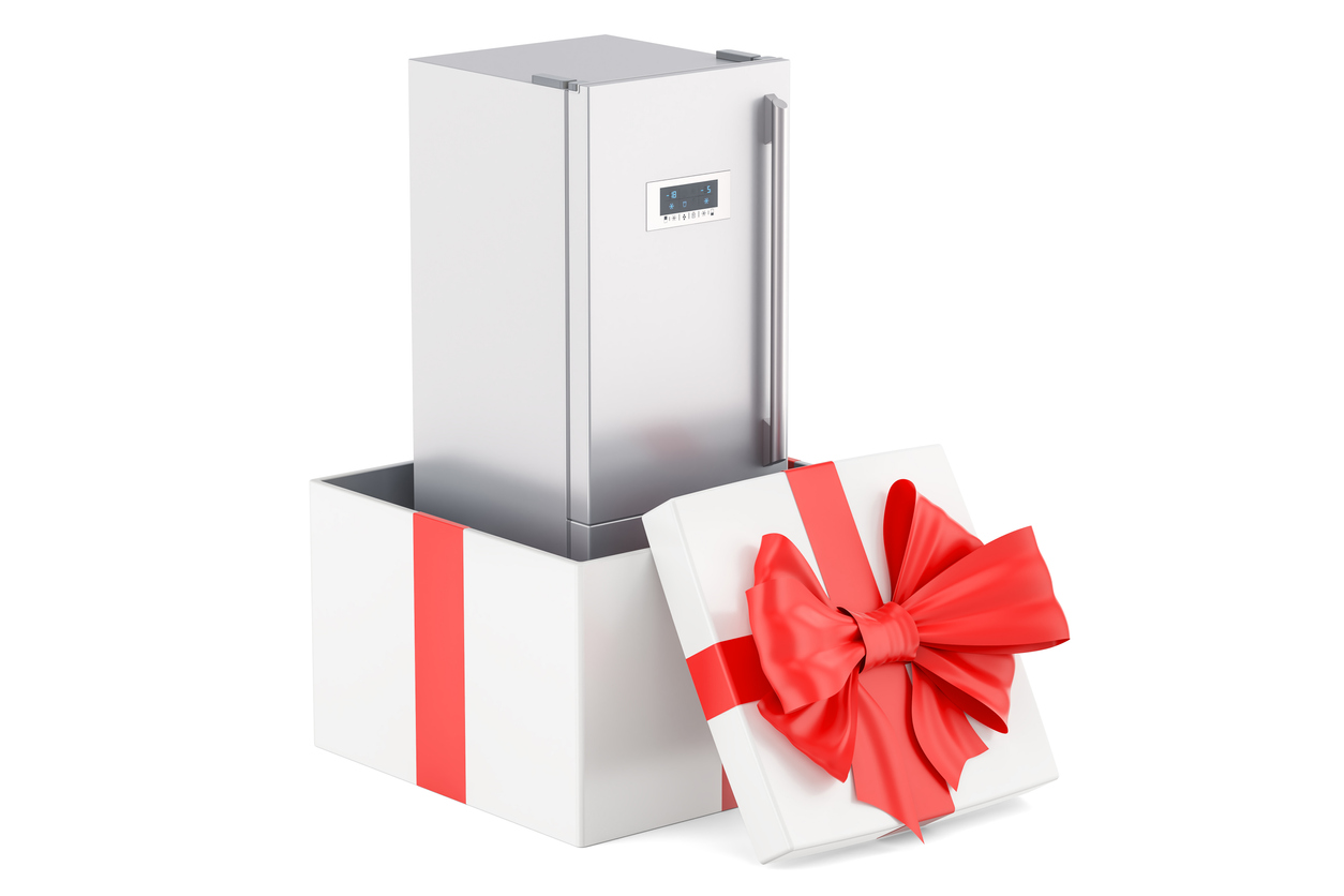 A refrigerator wrapped in a bow coming out of a box 