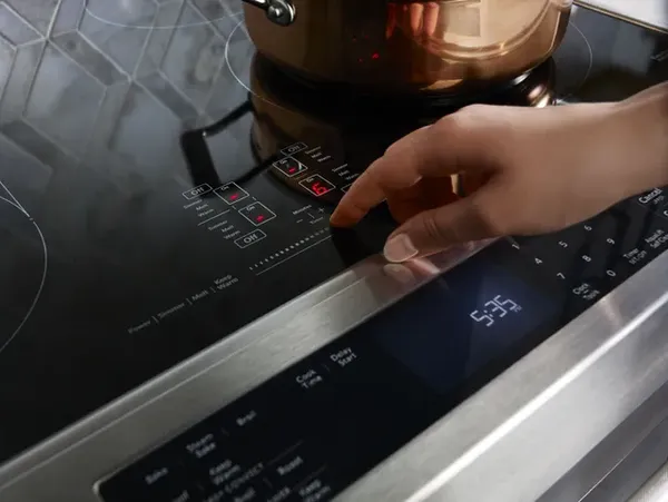 A person selecting a setting on the KitchenAid KSEB900ESS range