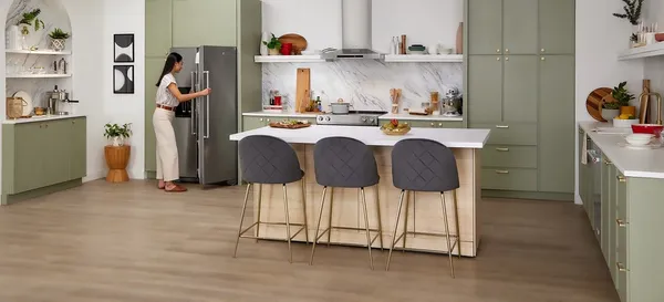 A woman looking through a KitchenAid side by side refrigerator in a kitchen 