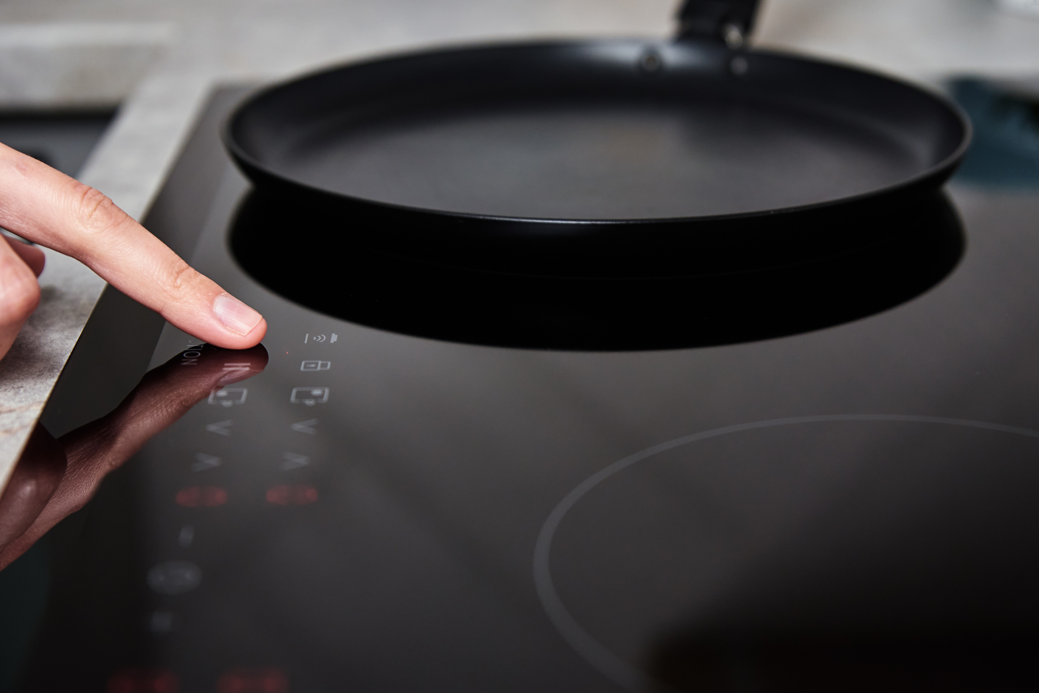A person selecting a heat control on a cooktop 