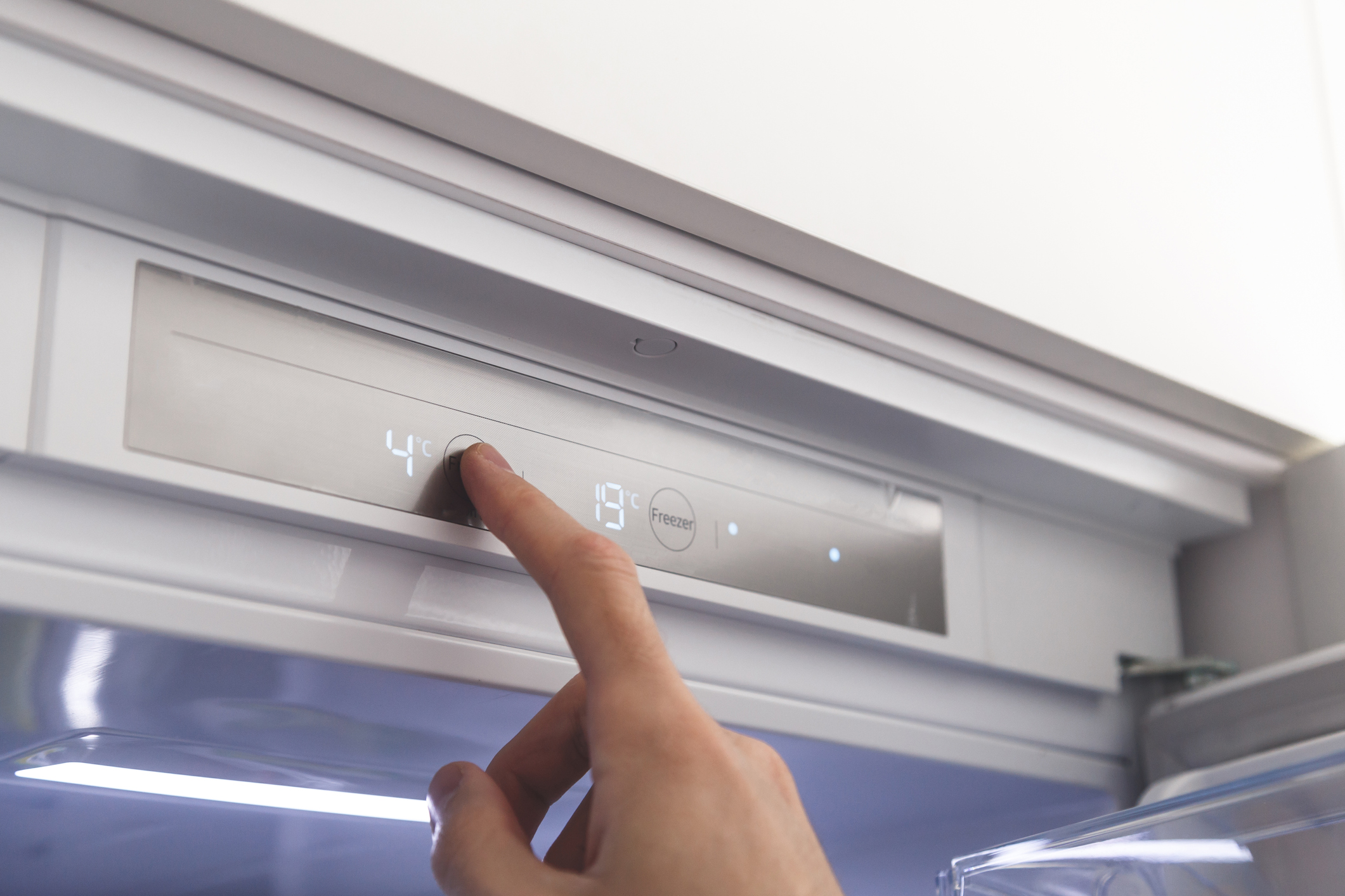 A person adjusting the temperature on a refrigerator 