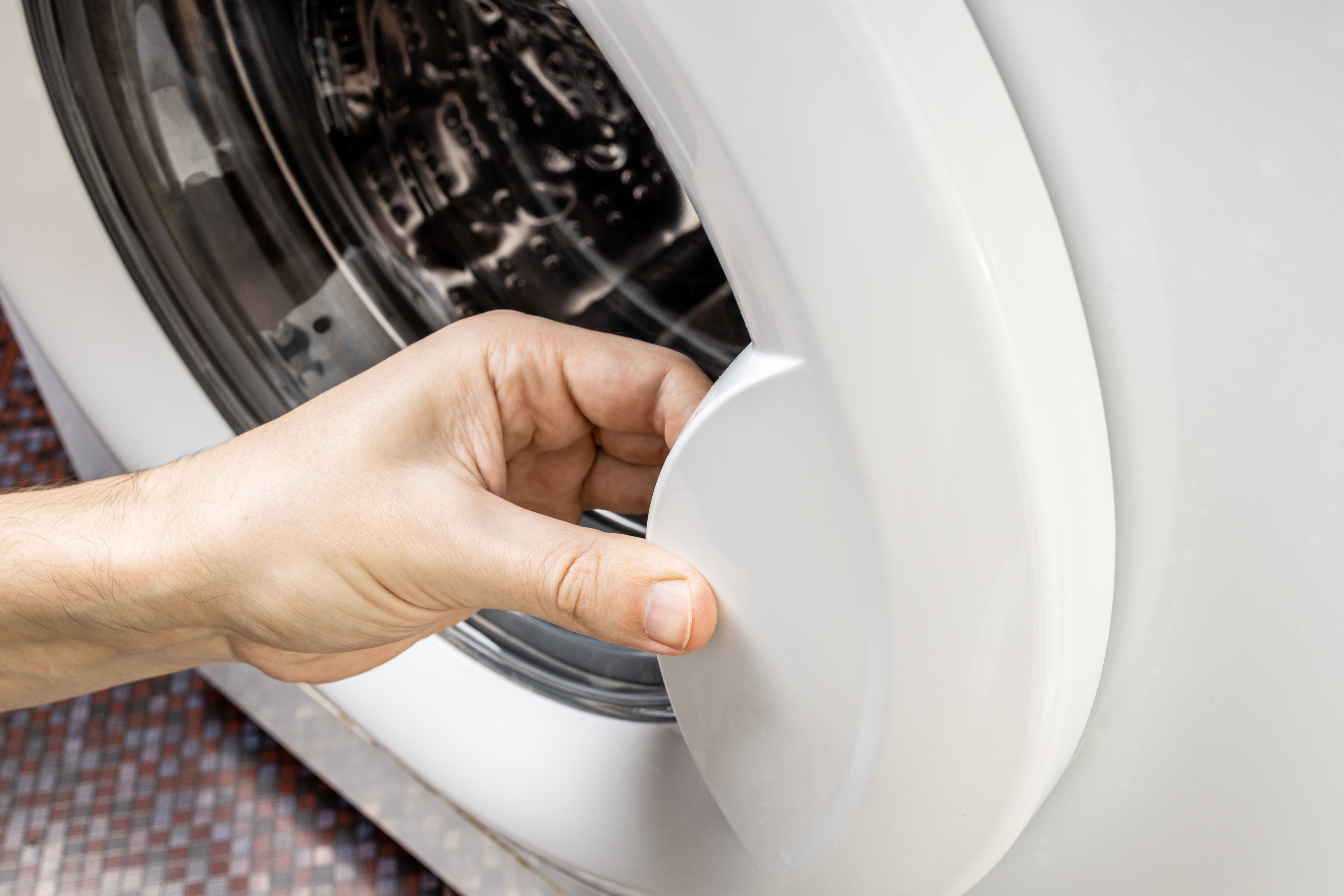 A close-up of a person opening a washer door 