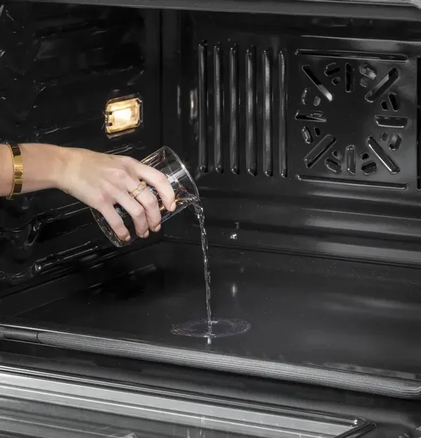 A person using the steam clean feature on the Café CTS70DP2NS1 oven