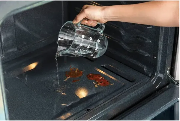 A person pouring water into the GE JTS3000SNSS wall oven 