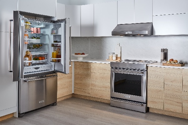 A kitchen with a KitchenAid refrigerator, range, and range hood 