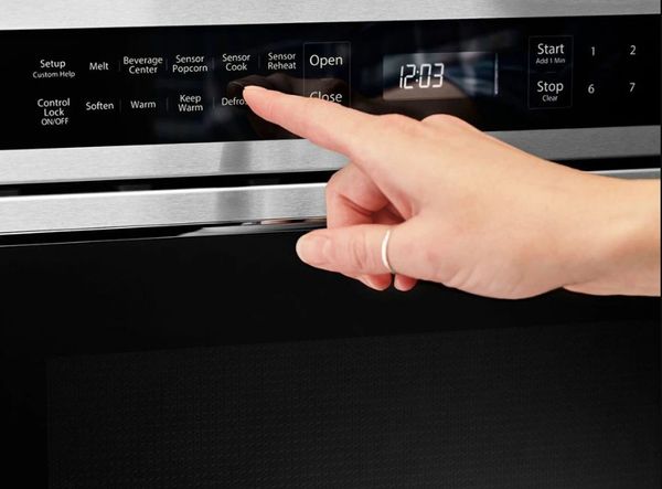 A person selecting a cooking mode on the KitchenAid KMBD104GSS microwave drawer control panel
