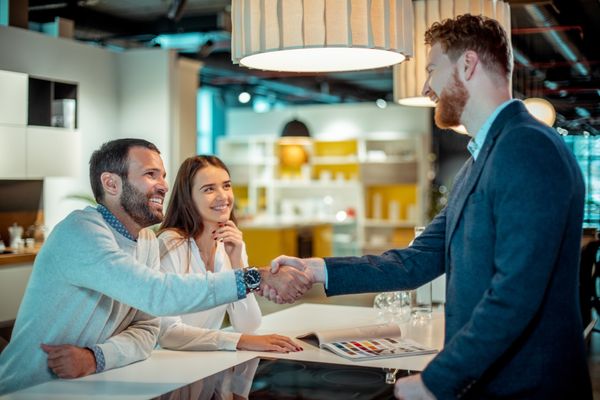 A suited appliance dealer smiling while shaking hands with buyers 
