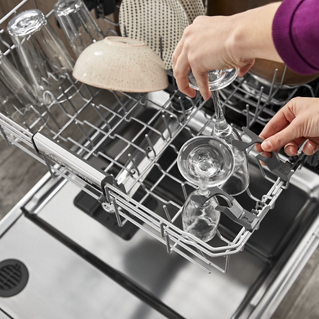 A person using the fold-down tines on a KitchenAid dishwasher