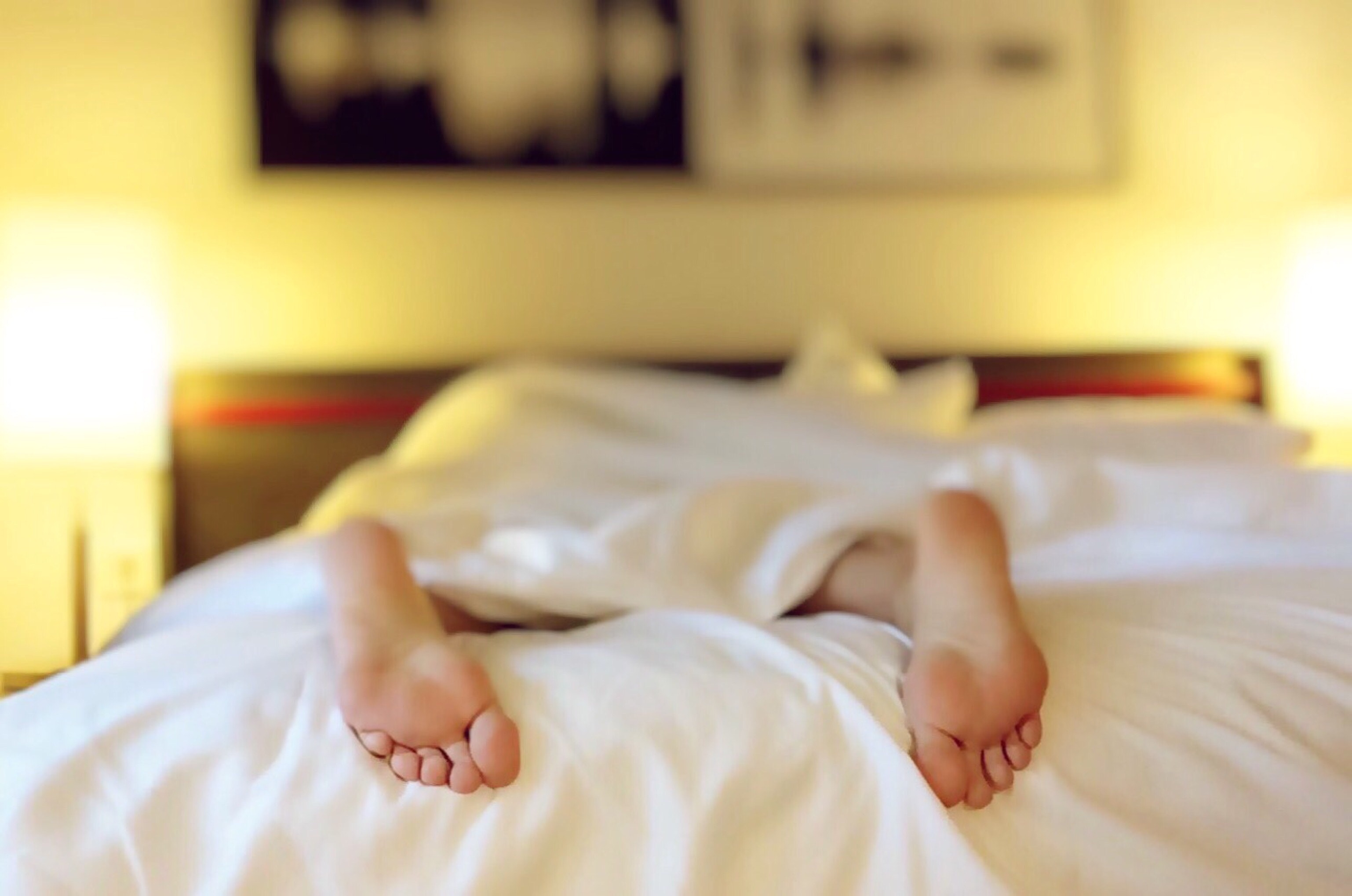 A person sleeping on a mattress with their feet sticking out 