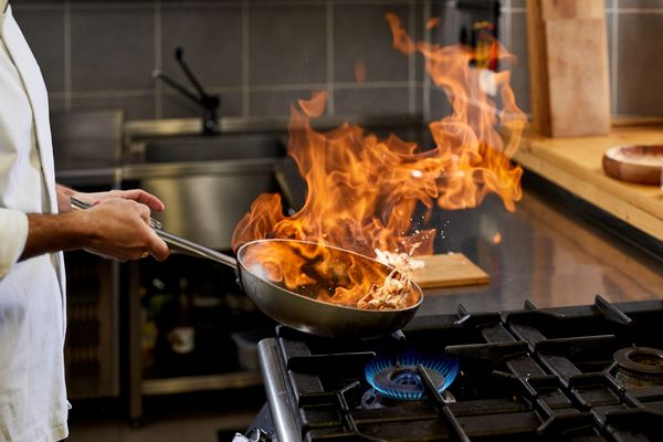 A person doing flambe on a gas range 