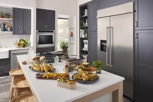 The KitchenAid KBSD708MPS refrigerator featured in a kitchen with a variety of grilled foods