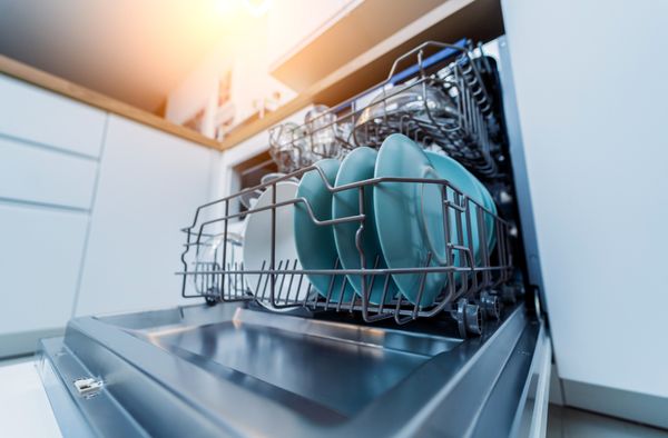 A close-up of an open, fully loaded dishwasher 