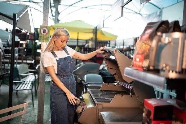 A woman inspecting a grill at a store 