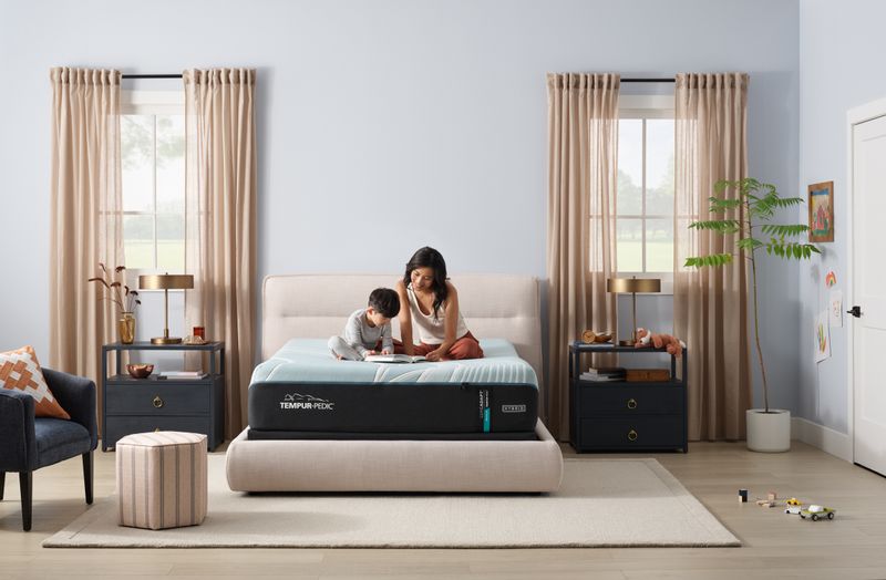 Contemporary bedroom with mother and son sitting on top of mattress