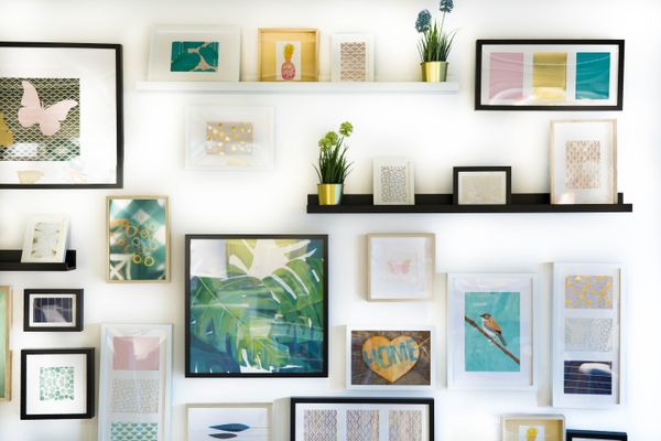 A wall decorated with different prints, shelves, and home accents