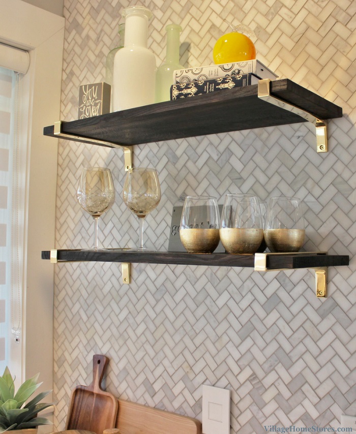 black charred shelves with gold wall brackets on wall with marble mosaic tile