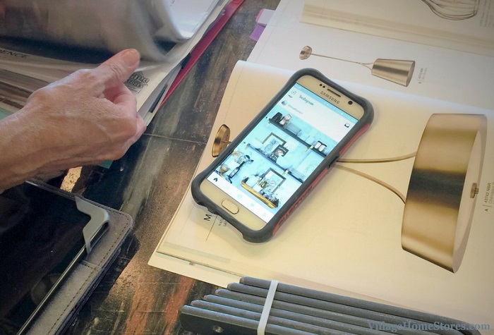 customer looking through binder of magazine pages with pile of lighting catalogs and smartphone also shown