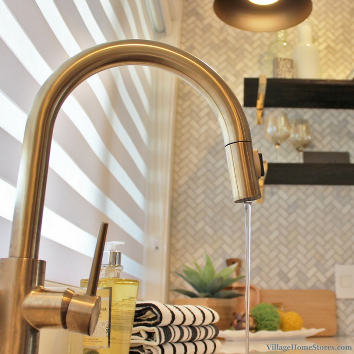 close up of gold Kohler kitchen faucet with pull down sprayer and water on
