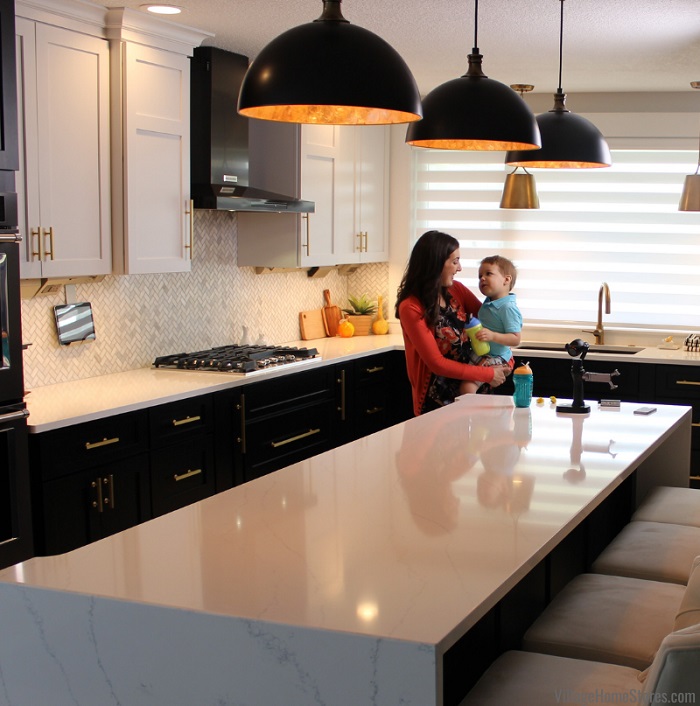 Women with brown hair holding young boy at kitchen island with black pendant lighting above
