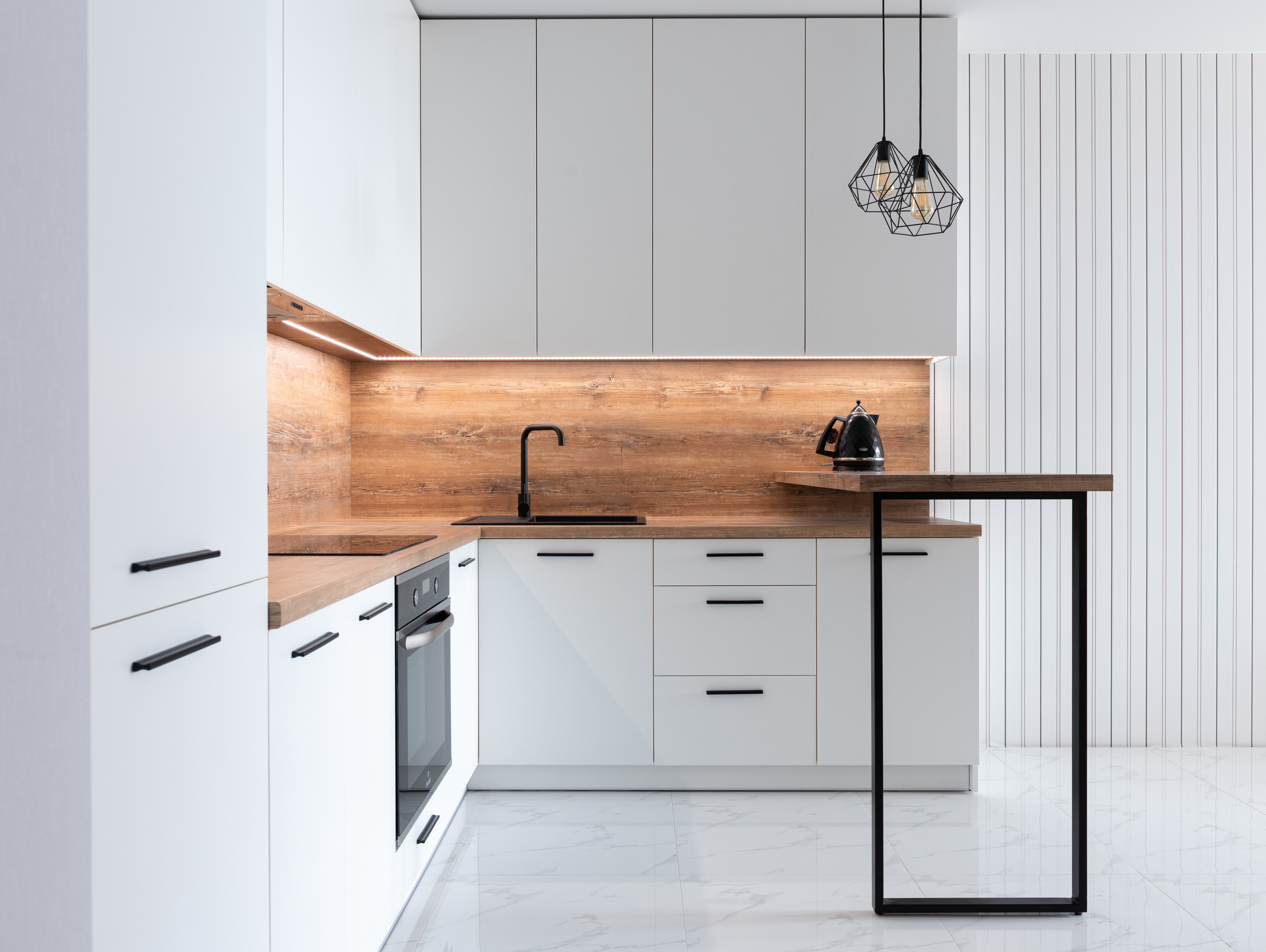 A modern white kitchen with a wood blacksplash