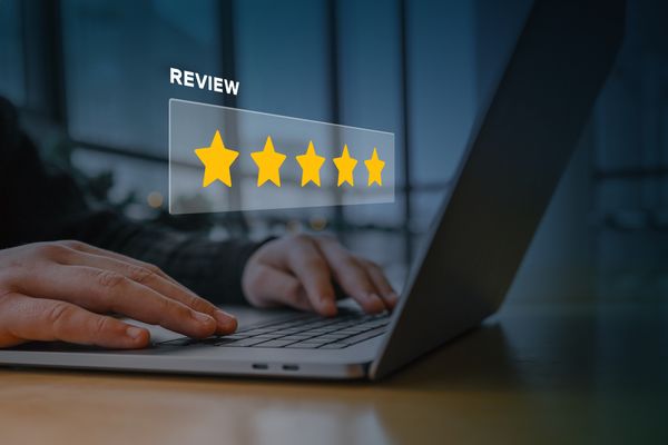 A man on a laptop with a 5-star review graphic overlay 