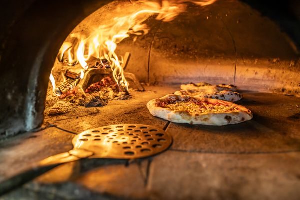 A close-up of a pizza cooking in a brick oven