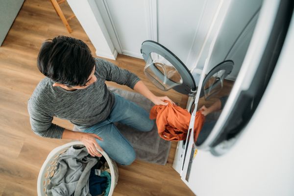 Overhead view of a man removing clothes from a stacked washer and dryer 