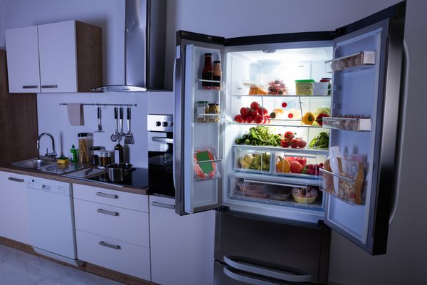 A French door refrigerator with its doors open in a dark kitchen
