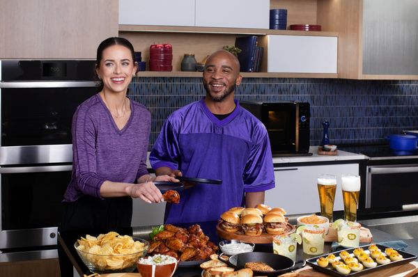A couple happily smiles as they prepare smoked meat for guests