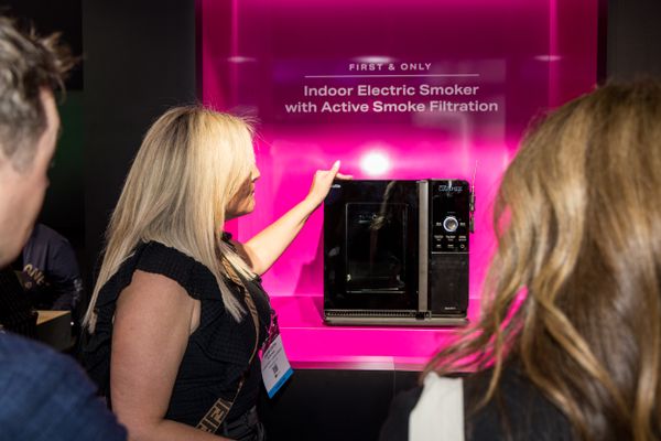 A woman inspects GE Profile's industry-first indoor meat smoker