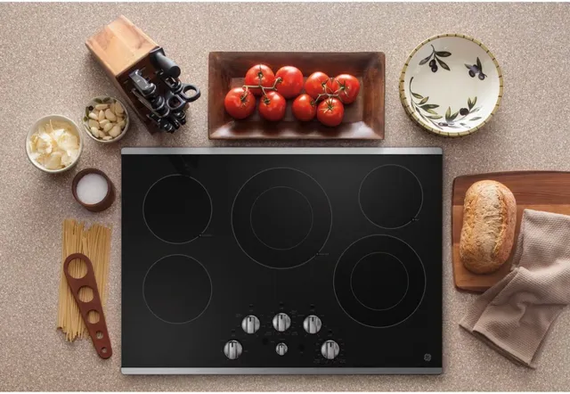Top view of a GE black electric cooktop with various dinner ingredients around it