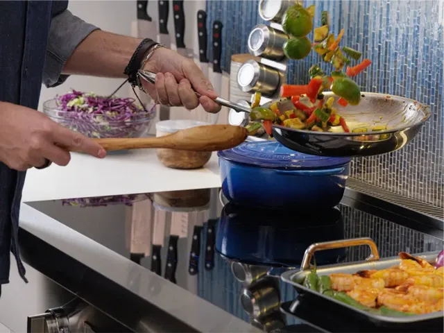 Credit: BSH Group, Thermador | Close view of a man cooking stir fry on a Thermador induction range