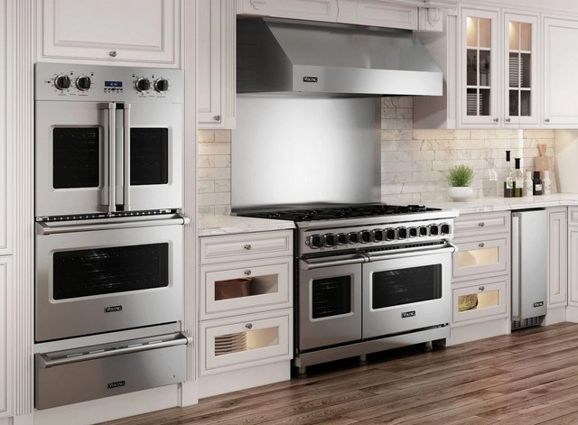 Front view of a modern kitchen with white cabinetry and a stainless steel Viking double wall oven, range, and range hood.