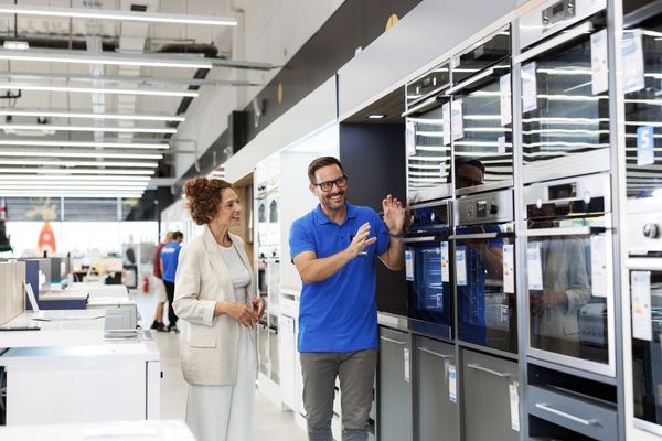 An appliance salesman showcasing ovens to a  t