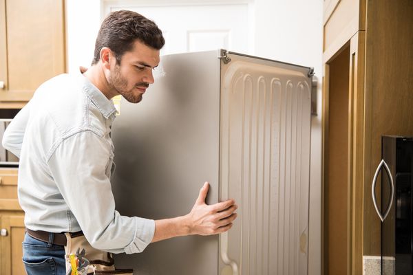 An appliance tech installing a fridge in a cutout 
