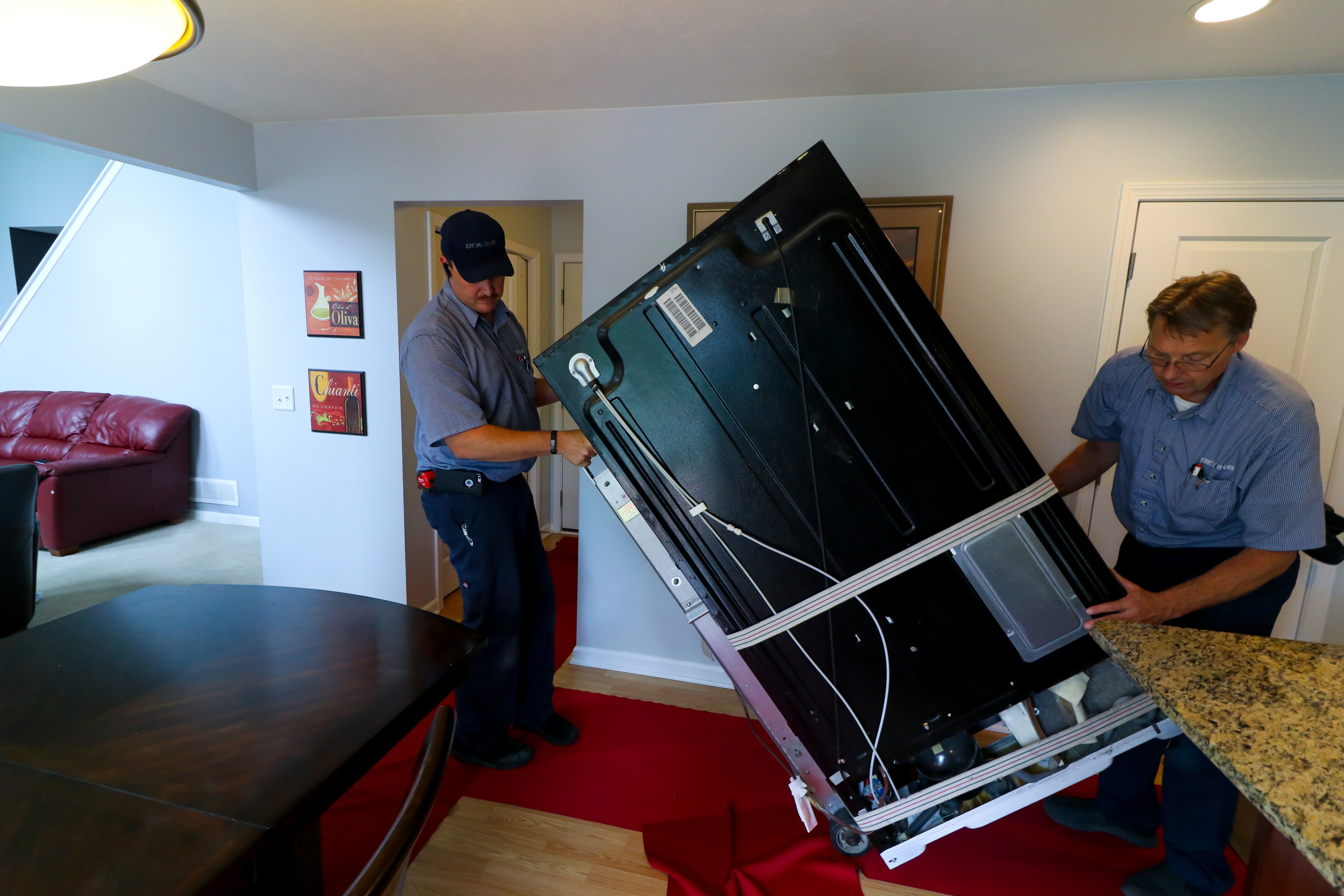 Two Bekins workers carefully remove an old appliance from a home