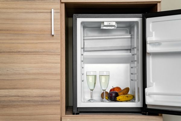 A close-up of a built-in beverage refrigerator in a wooden cabinet 